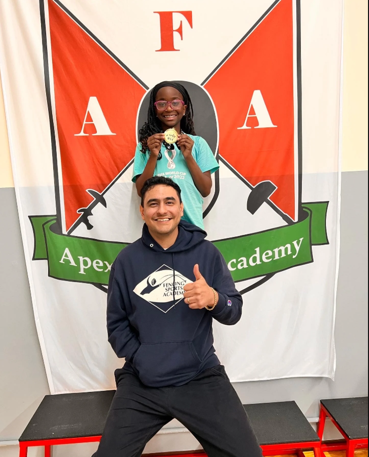 Teacher in a blue sweatshirt with an award winning student