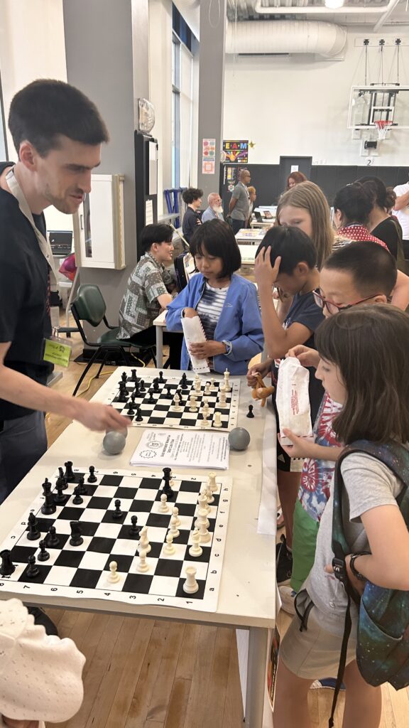 chess teacher shows students chess board on a table
