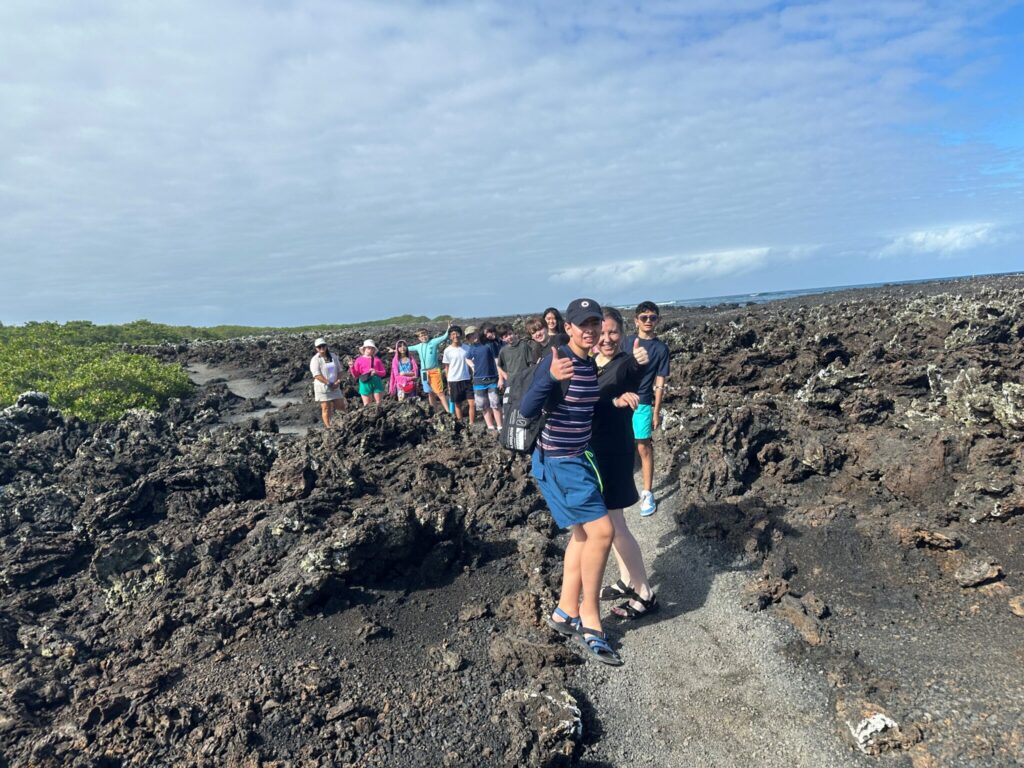 Hiking through volcanic rock and giving thumbs ups and smiles.