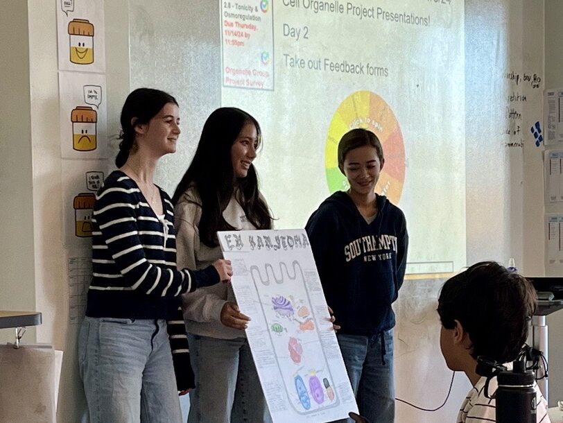 three female students present a biology poster on cell organelles