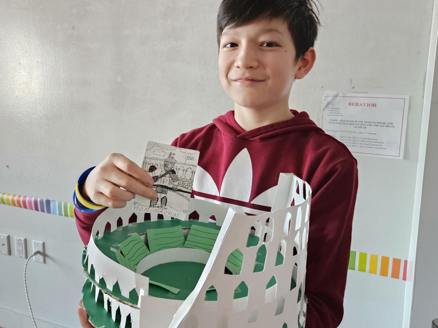 male student holiding up a latin project 