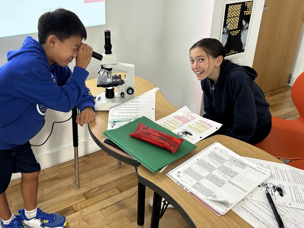 grade 6 students looking through a microscope