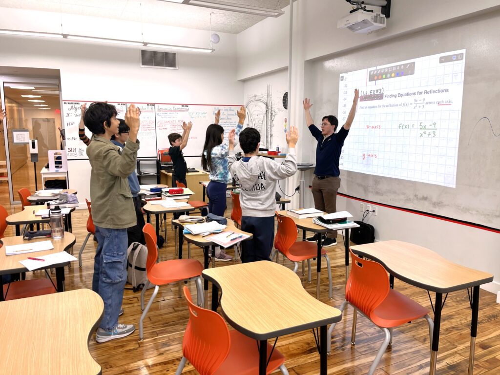 upper school students act out math with their teacher in the classroom
