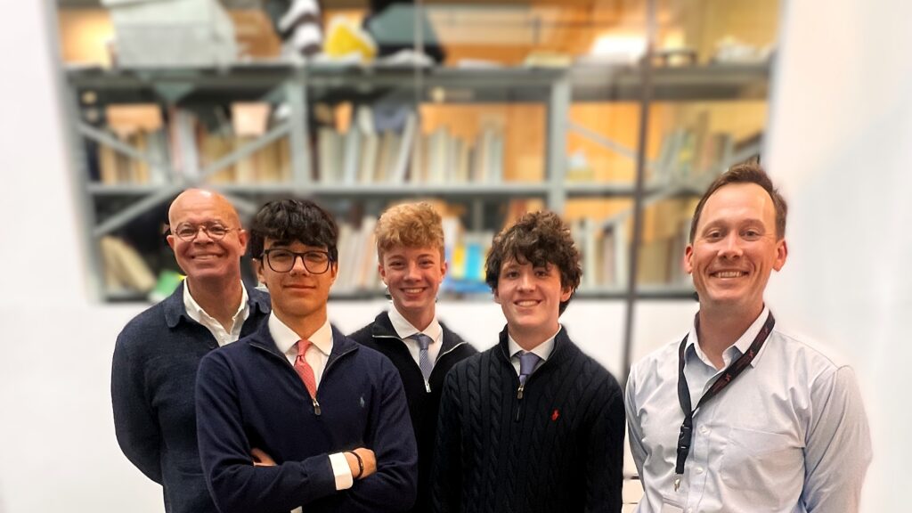 The founding investors club students stand on the staircase inside the Upper School with CEO of Spring Education Group (SEG) Michael Collins and club advisor, Kirk Murphy.