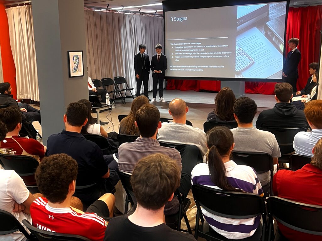 three young men present a powerpoint about investments in front of an audience 