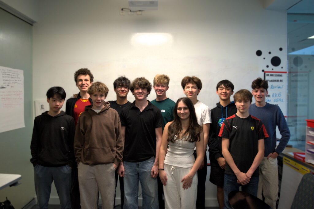 The 11 students in the 2025-26 Young Investors Club stand in a classroom taking a photo for the yearbook.