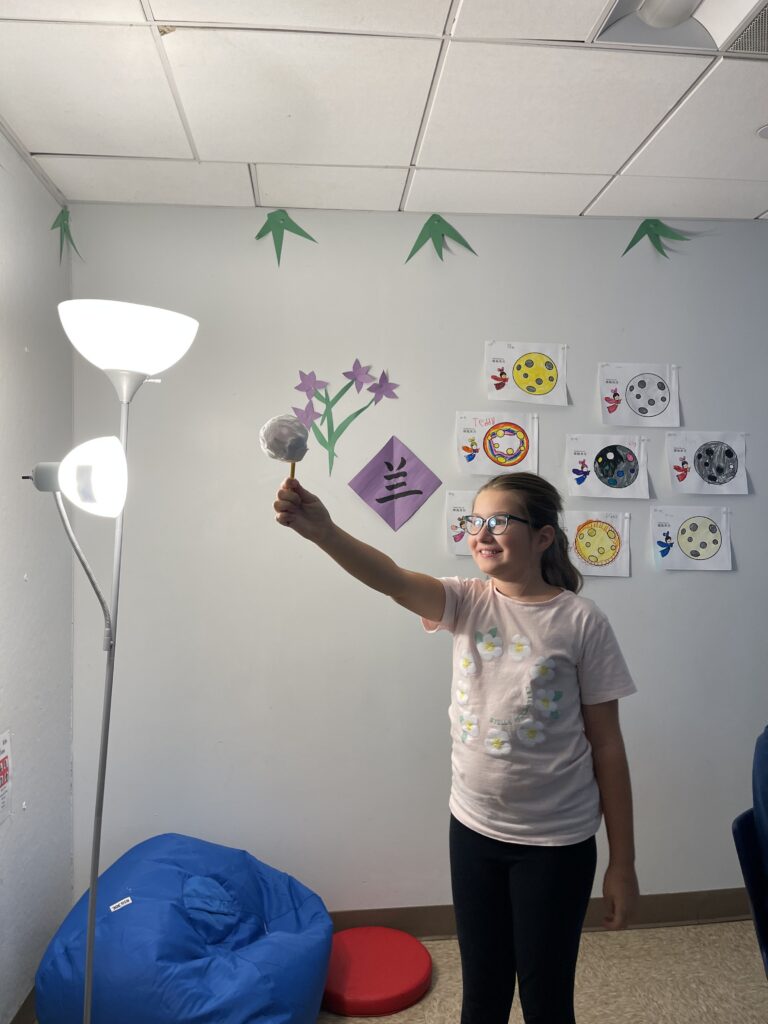 student holding up a moon prototype in the mandarin classroom