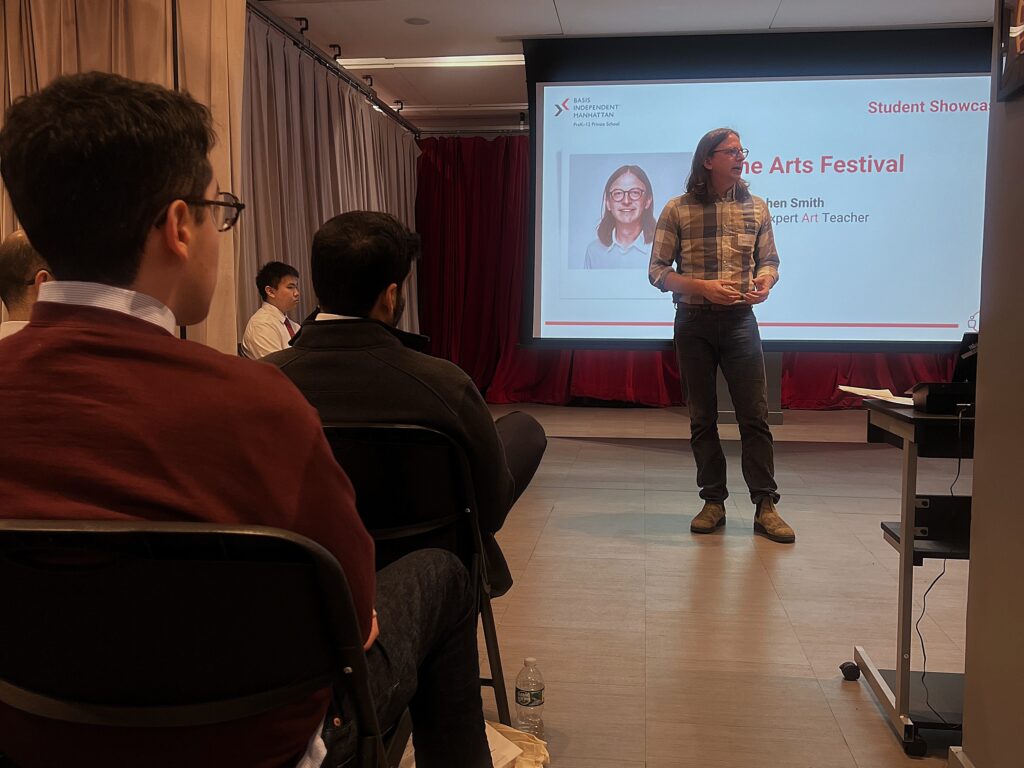 male teacher standing in front of a presentation screen and talking to an audience
